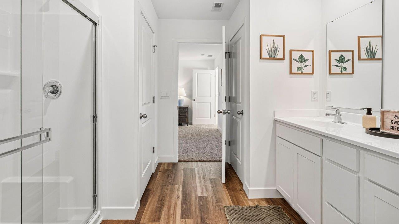 Greenbrier Pine Model Home - primary bedroom ensuite bathroom with lvp flooring, dual sink vanity, cultured white marble counters, walk in shower