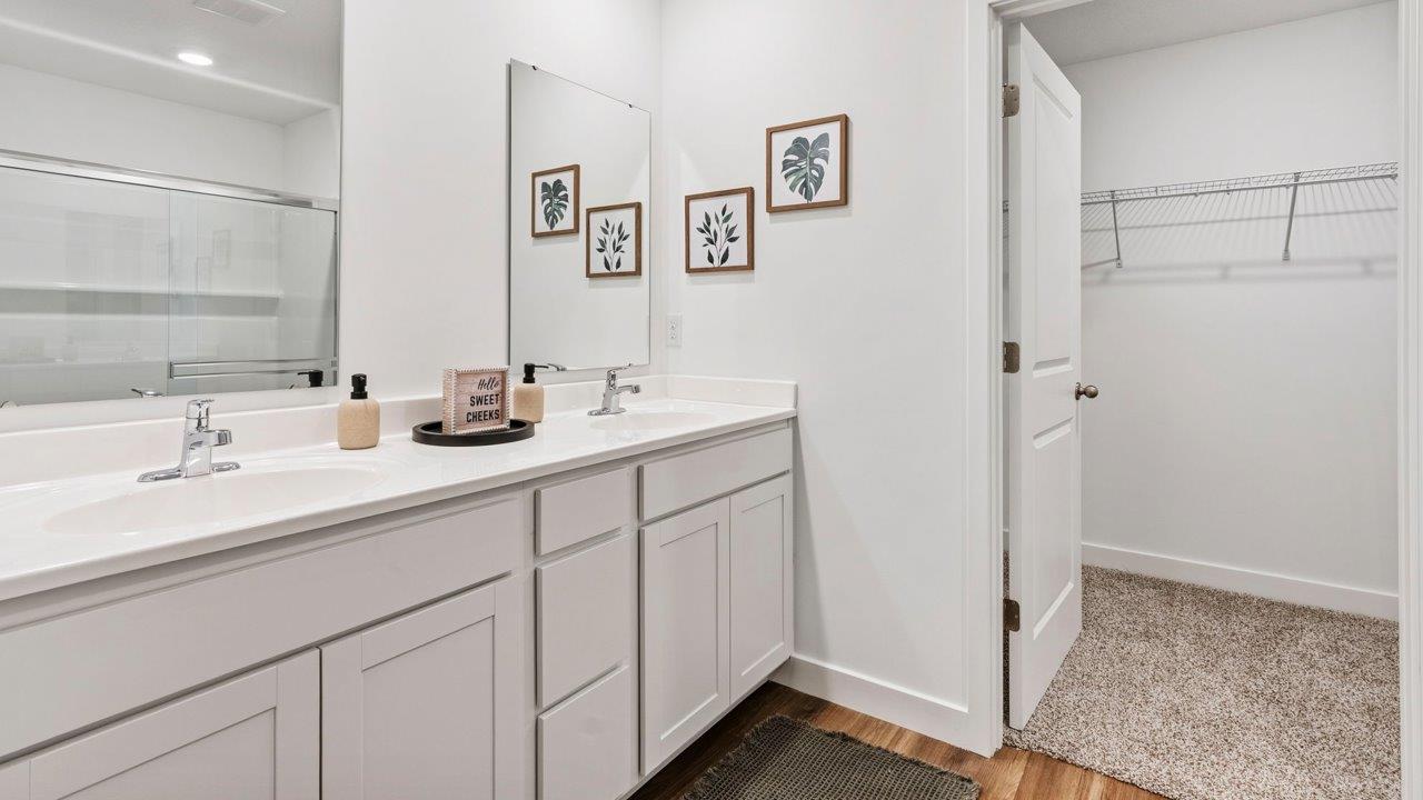 Greenbrier Pine Model Home - primary bedroom ensuite bathroom with lvp flooring, dual sink vanity, cultured white marble counters, walk in shower
