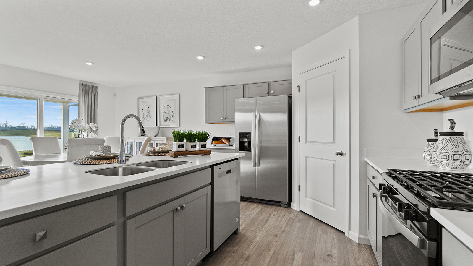 chatham kitchen with grey cabinets, quartz counters, pantry, appliances, and center island with bar seating