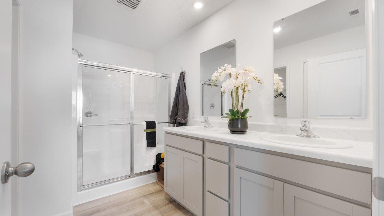 bellamy primary ensuite bathroom with dual sinks, walk-in shower, and private water room