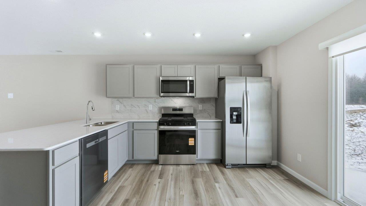 kitchen with grey cabinets, stainless steel appliances, and quartz countertops