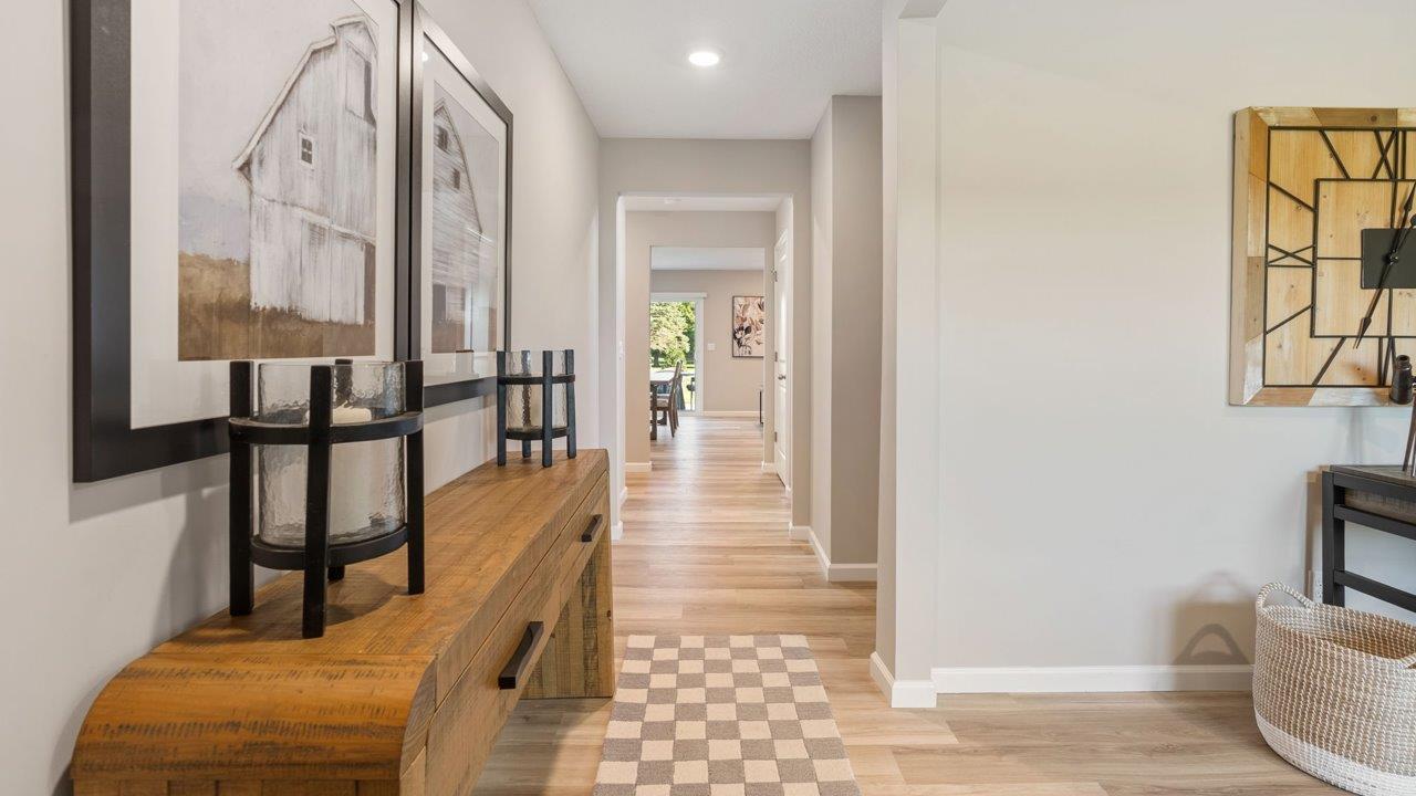 Greenbrier Stamford Model Home - foyer with mohawk avery luxury vinyl plank flooring, popular grey flooring, furnished with entry table, rug, and artwork leading to study and open layout living room