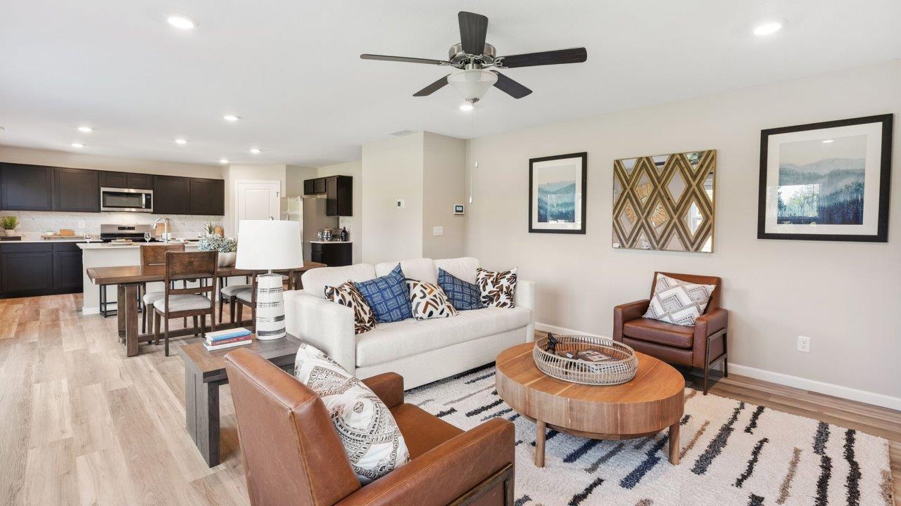 Greenbrier Stamford Model Home - living room with ceiling fan, mohawk avery lvp flooring, large windows, and popular grey windows