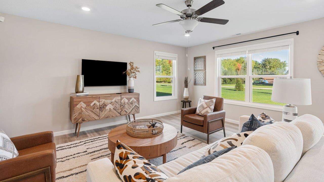 Greenbrier Stamford Model Home - living room with ceiling fan, mohawk avery lvp flooring, large windows, and popular grey windows