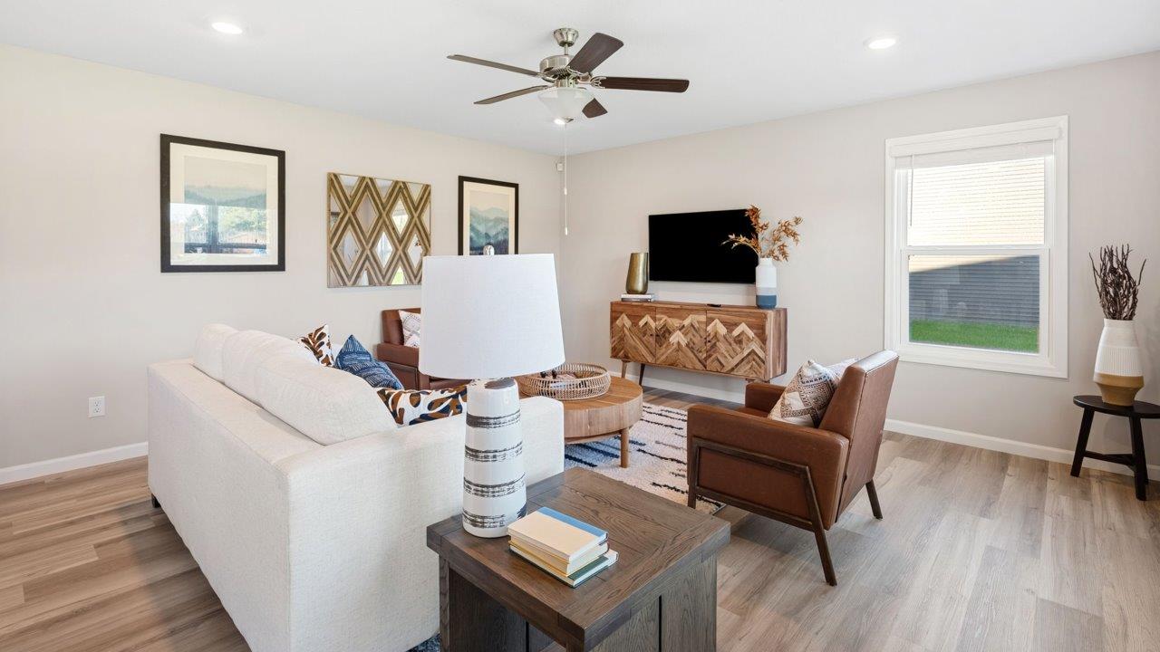 Greenbrier Stamford Model Home - living room with ceiling fan, mohawk avery lvp flooring, large windows, and popular grey windows