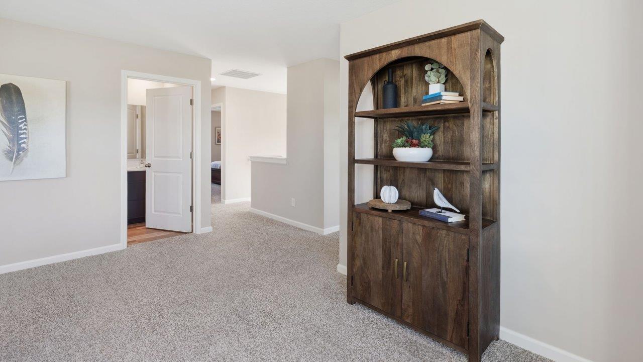 Greenbrier Stamford Model Home - second floor loft space with elk beige carpet and furnished with lounge chairs and bookshelf