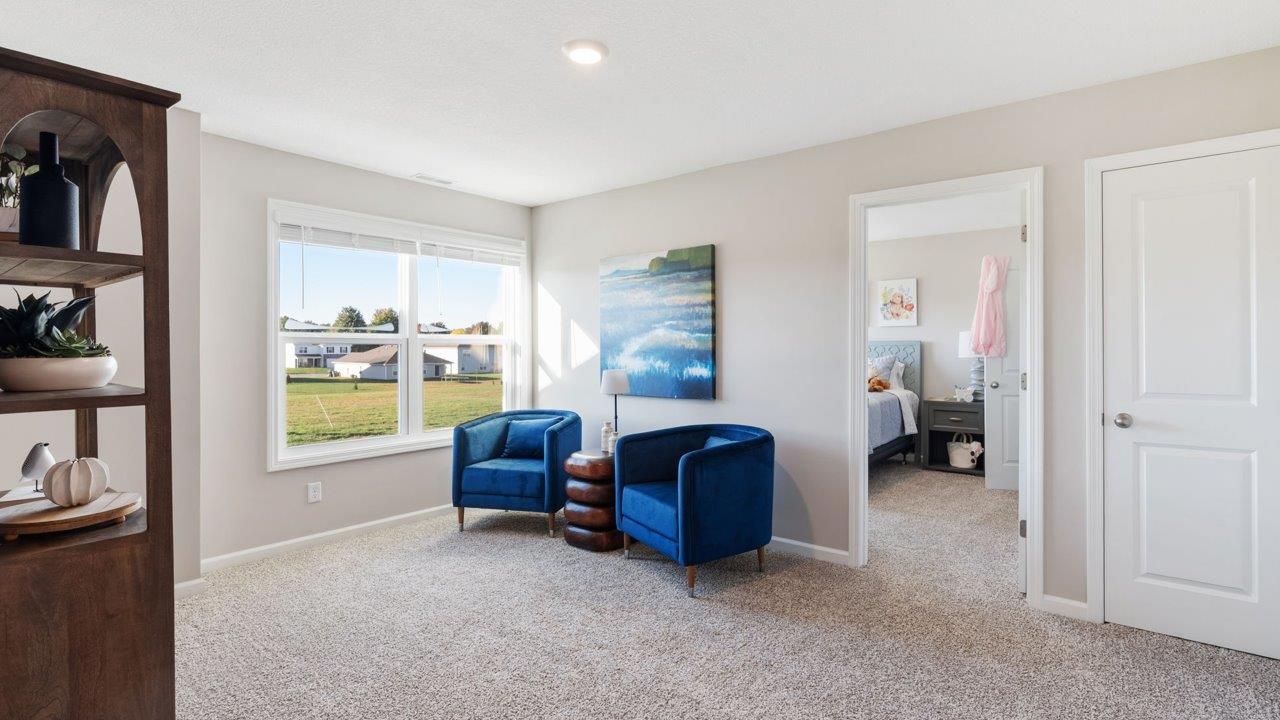 Greenbrier Stamford Model Home - second floor loft space with elk beige carpet and furnished with lounge chairs and bookshelf