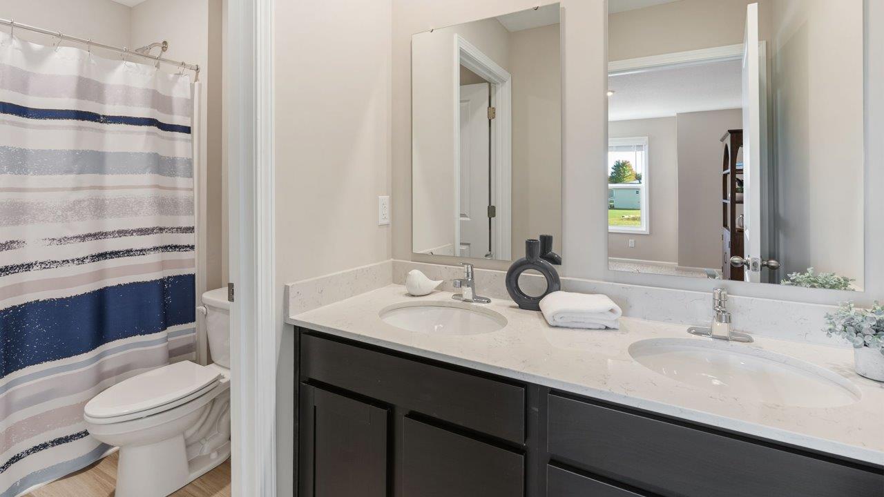 Greenbrier Stamford Model Home - full bathroom with dual sinks, private water room, and tub shower