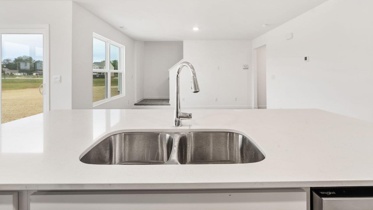 greenbrier cabral kitchen with white cabinets, stainless steel appliances, corner pantry, island with seating, and quartz countertops