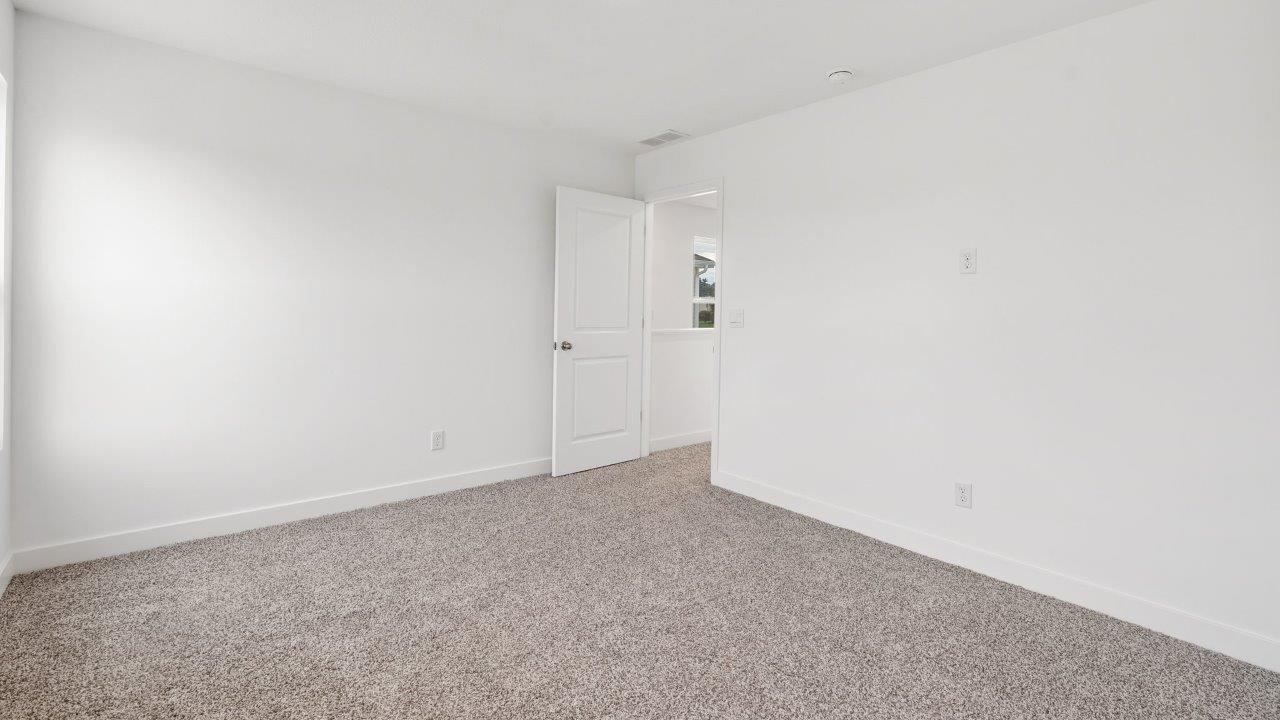 greenbrier cabral primary bedroom with ensuite bathroom and walk in closet with elk biege carpet flooring, 2 windows, and white walls