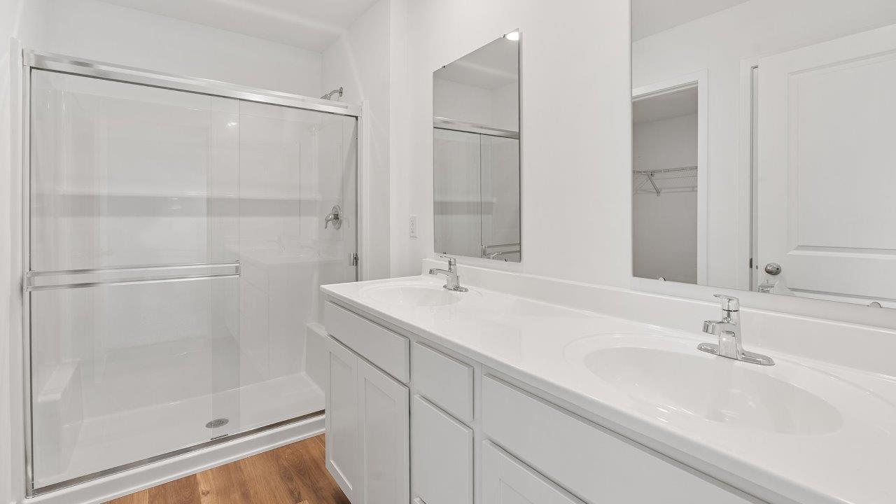 greenbrier cabral primary bedroom ensuite bathroom with dual sink vanity, lvp flooring, and walk in shower