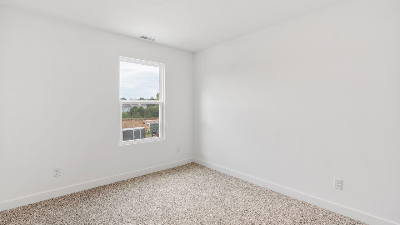 greenbrier cabral primary bedroom with ensuite bathroom and walk in closet with elk biege carpet flooring, 2 windows, and white walls