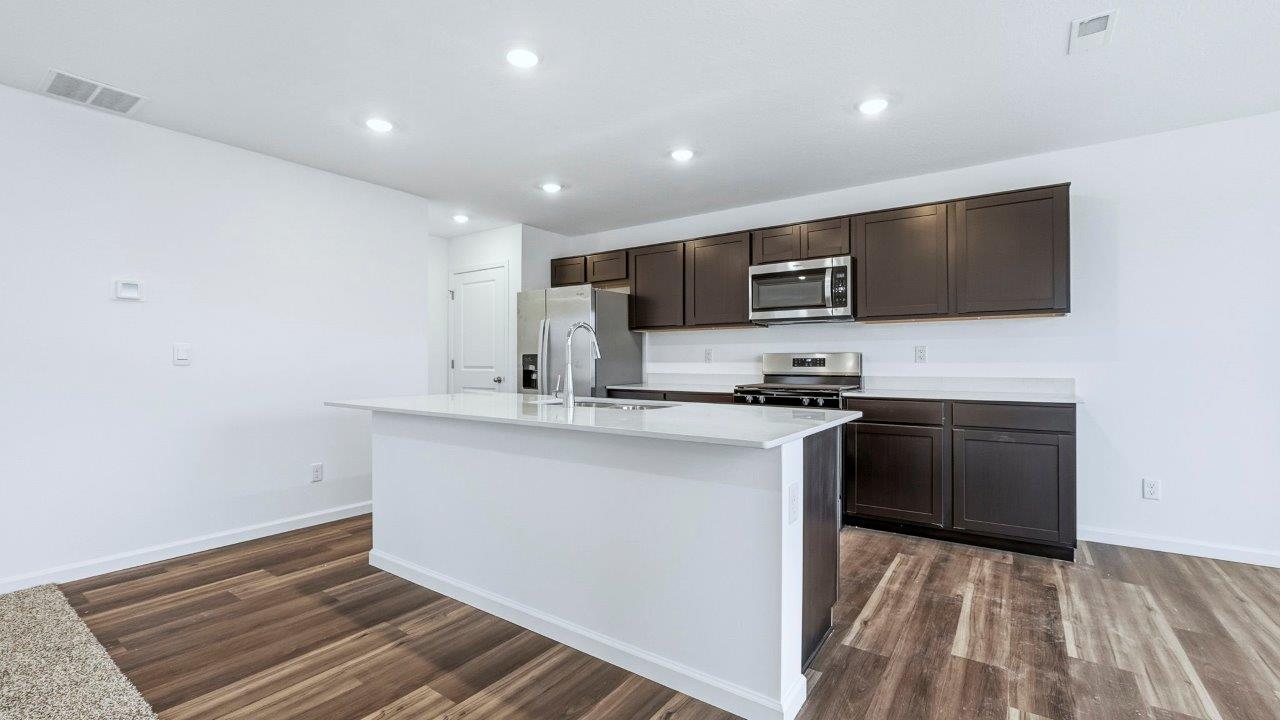 kitchen with dark brown cabinets, center island, lvp, stainless steel appliances, and more