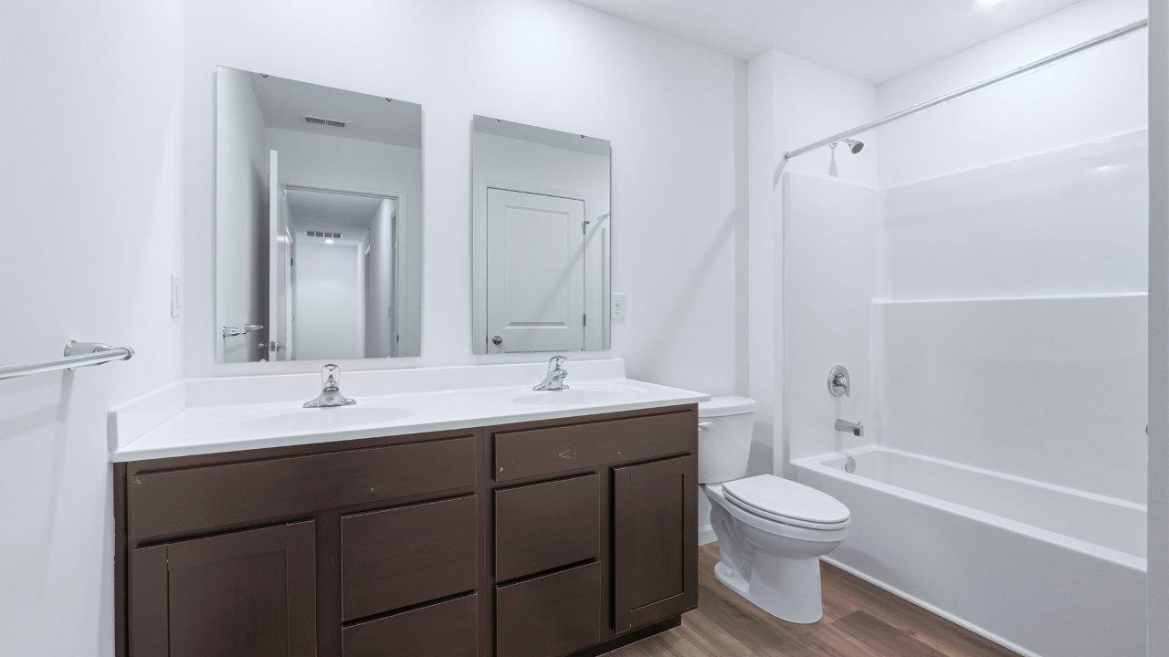 full bath with dual sinks and tub shower