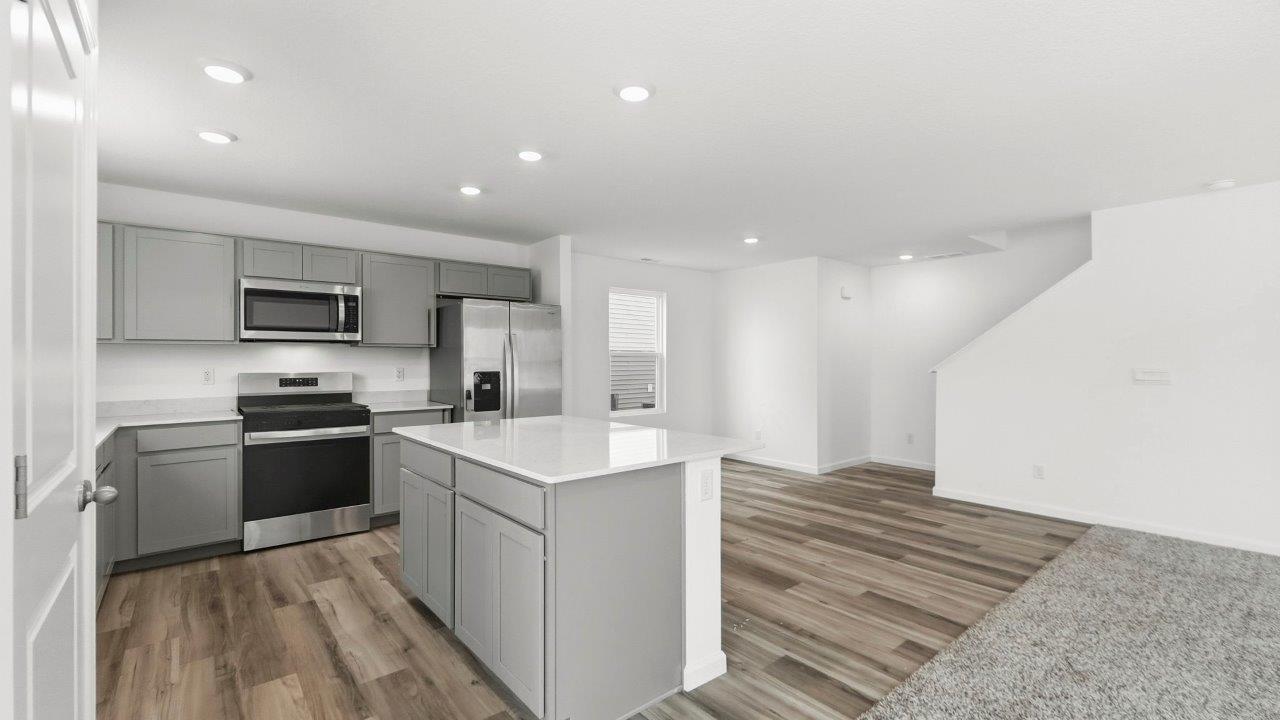 kitchen with grey cabinets, stainless steel appliances, quartz coutners, and large center island