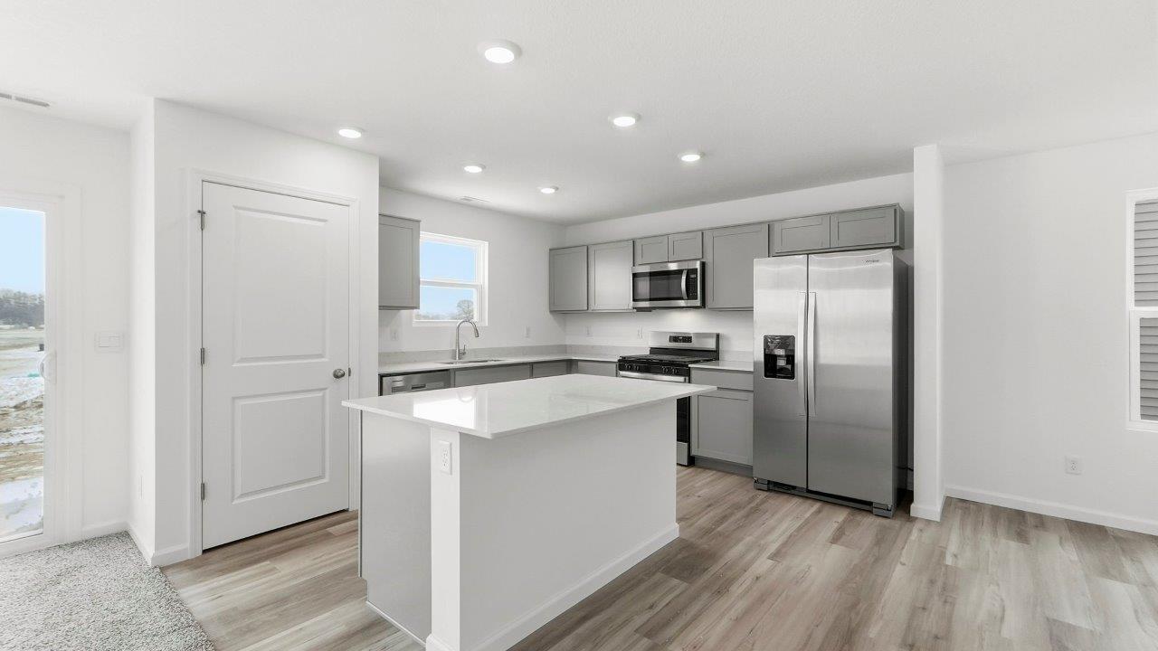 kitchen with grey cabinets, stainless steel appliances, quartz coutners, and large center island