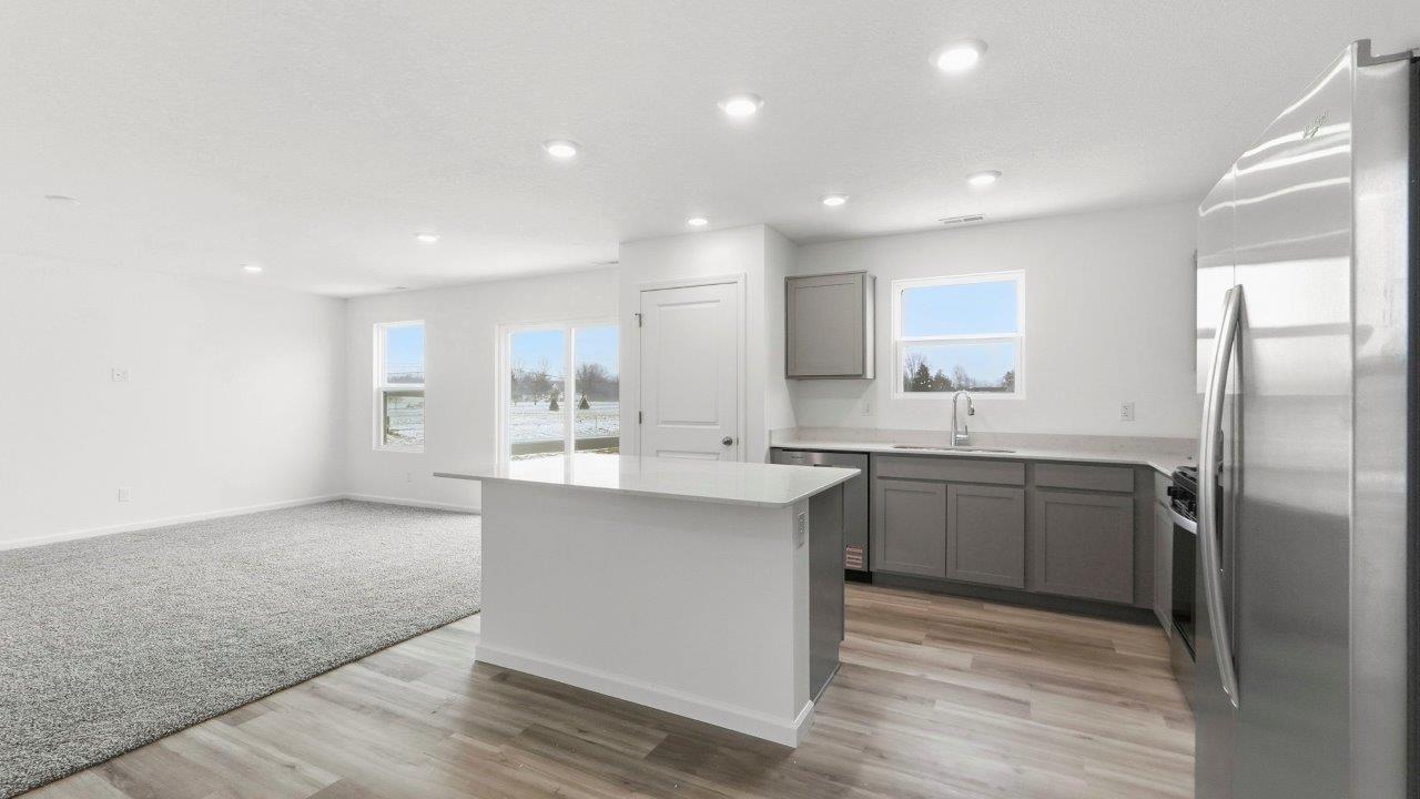 kitchen with grey cabinets, stainless steel appliances, quartz coutners, and large center island