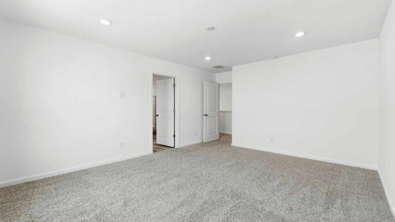 primary bedroom with carpet and ensuite bath and closet