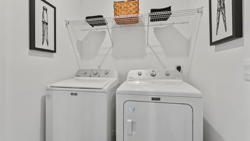 Riverwalk Aldridge model home - laundry room with washer and dryer, wire shelving, and LVP
