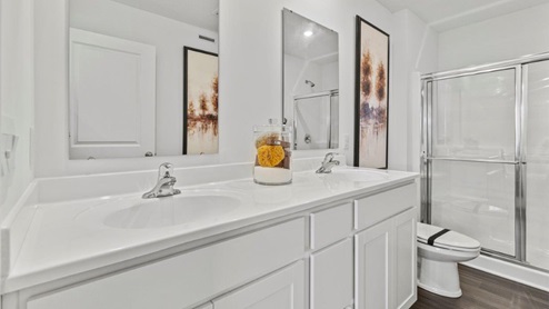 Riverwalk Aldridge model home - bathroom with dual vanity sinks with white marble countertops and walk in shower with LVP flooring
