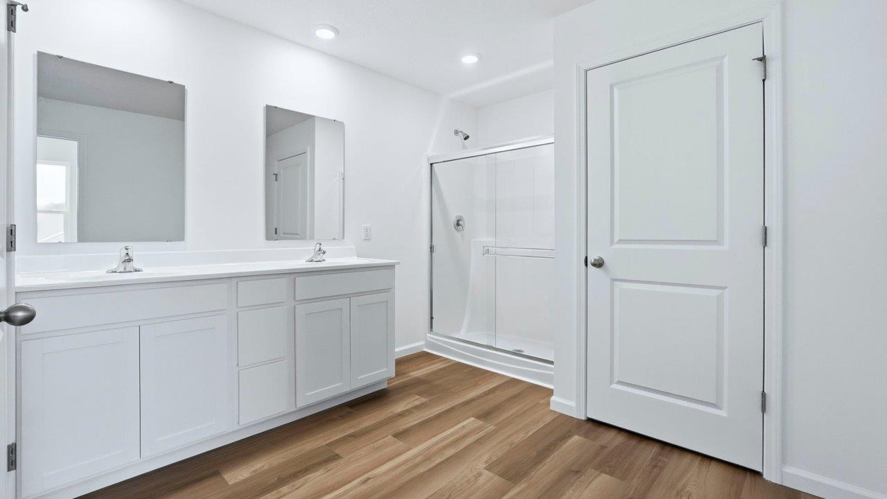 primary ensuite bathroom with dual sinks, walk in shower, lvp, and private water room