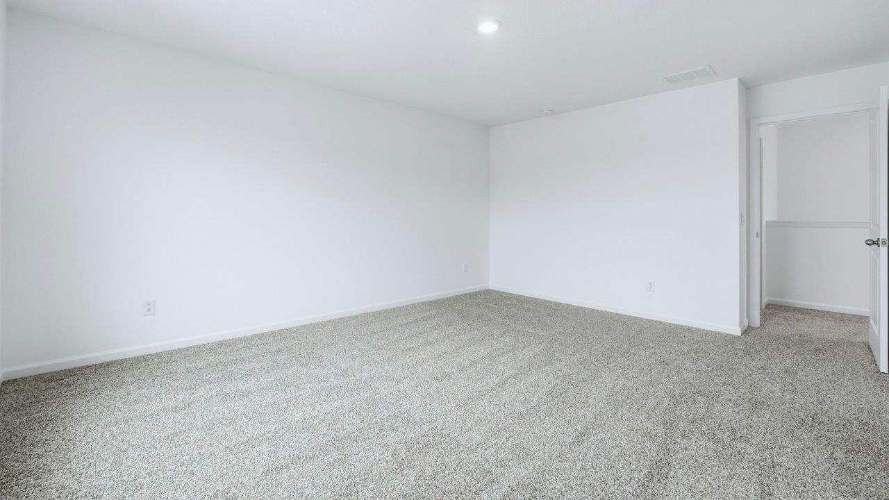 primary bedroom with ensuite bath and closet with carpet flooring