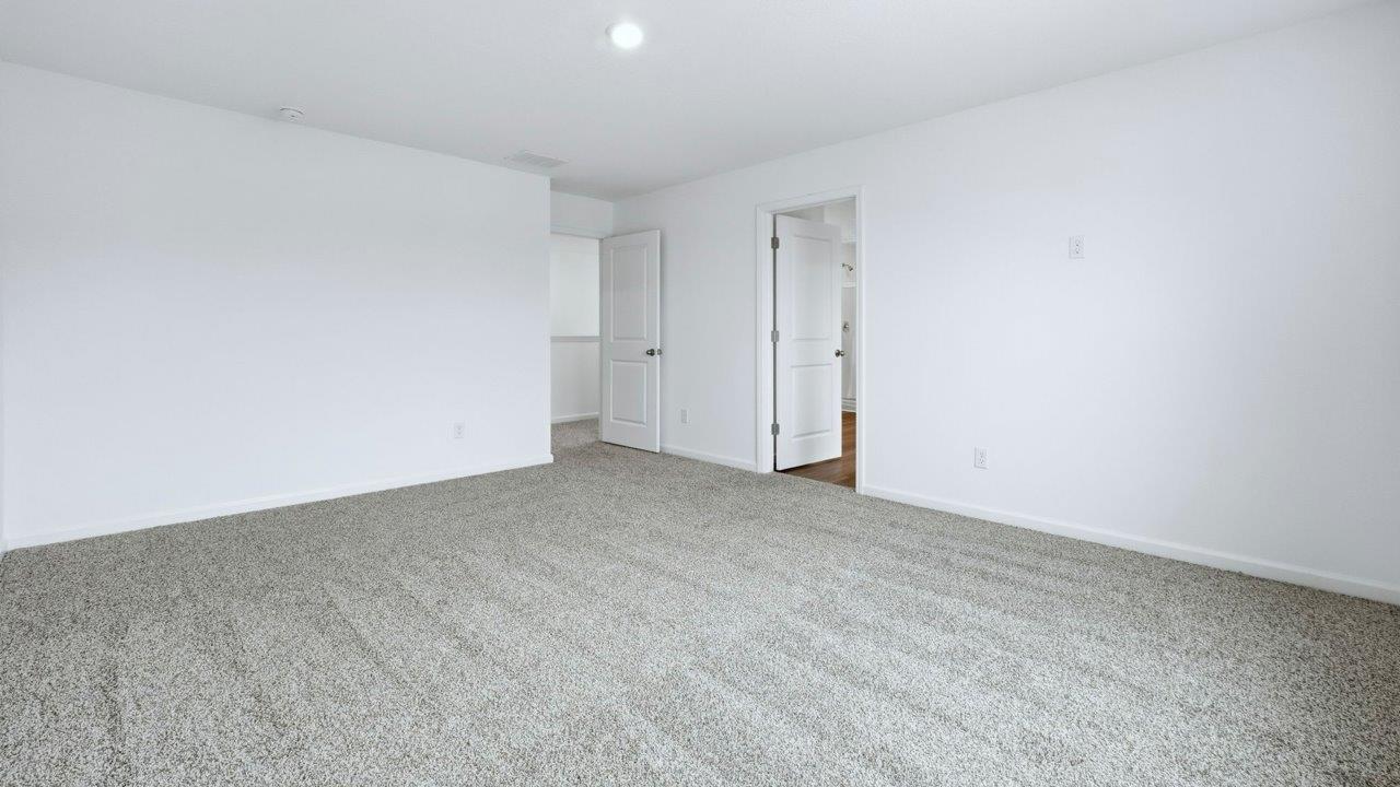 primary bedroom with ensuite bath and closet with carpet flooring