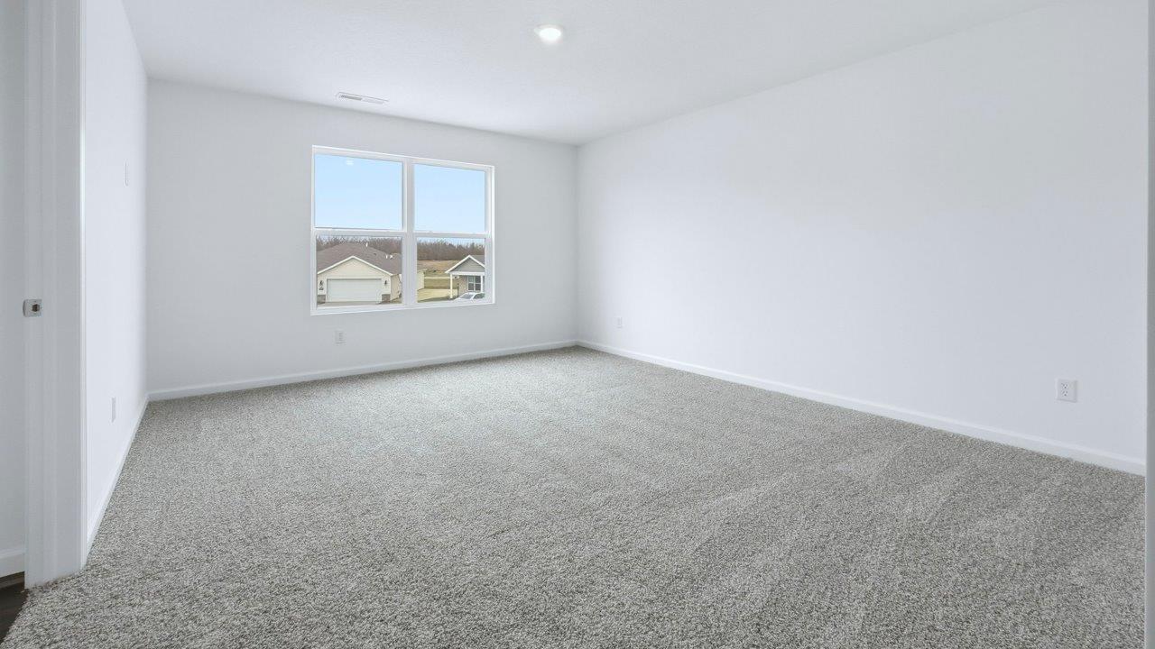 primary bedroom with ensuite bath and closet with carpet flooring