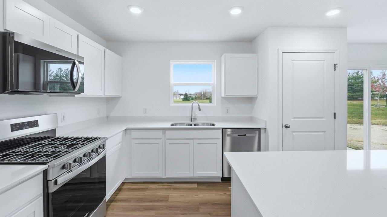 kitchen with white cabinets, quartz countertops, stainless steel appliances, center island, with lvp flooring