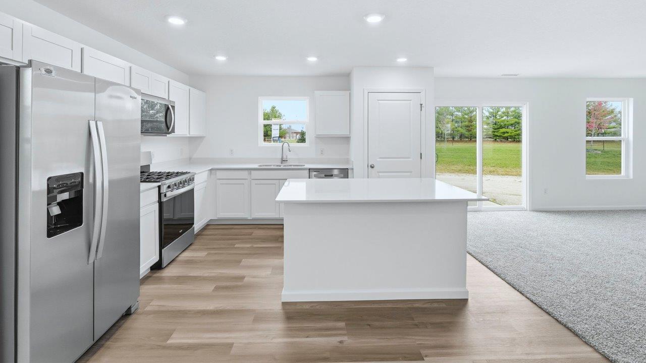 kitchen with white cabinets, quartz countertops, stainless steel appliances, center island, with lvp flooring