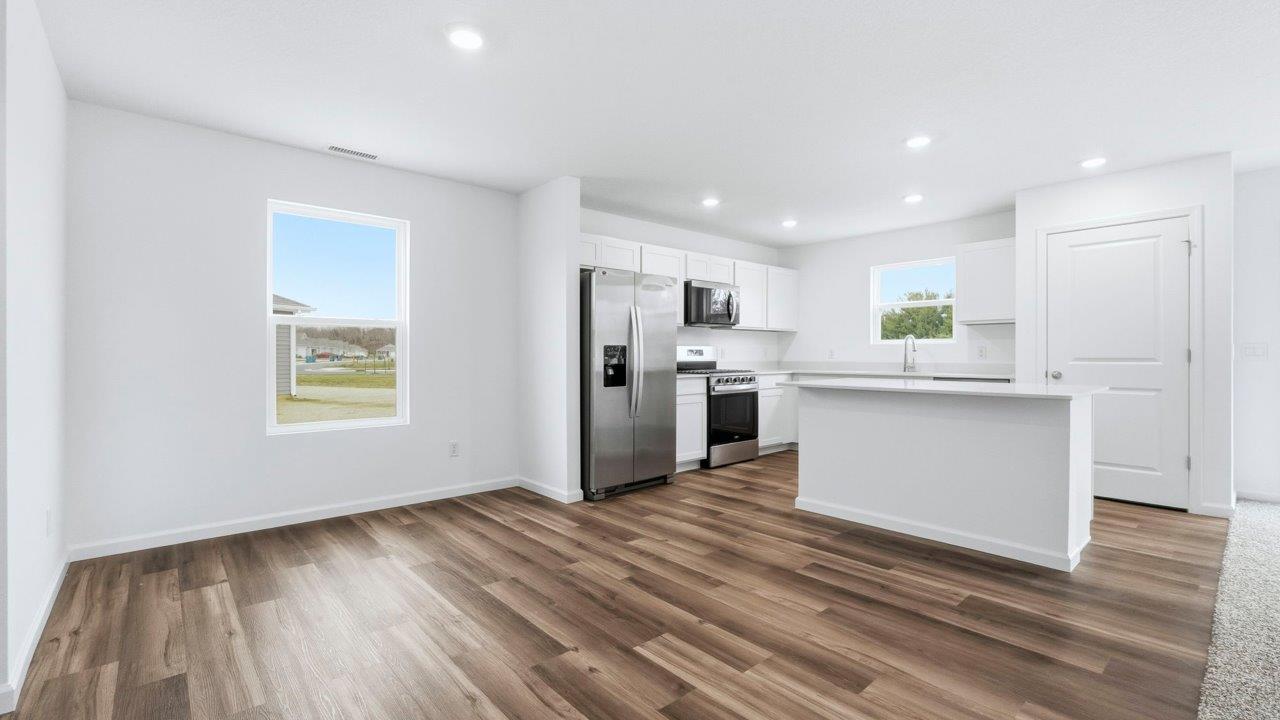 kitchen with white cabinets, quartz countertops, stainless steel appliances, center island, with lvp flooring