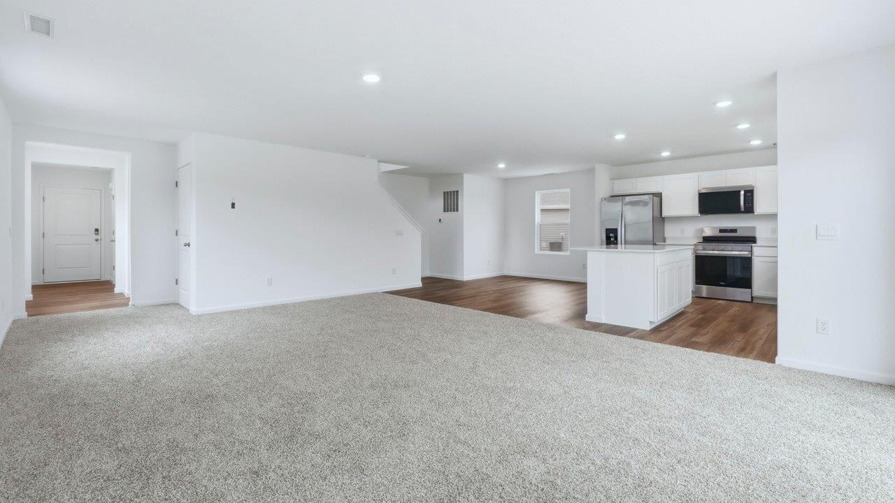 open layout living room and kitchen with carpet and lvp