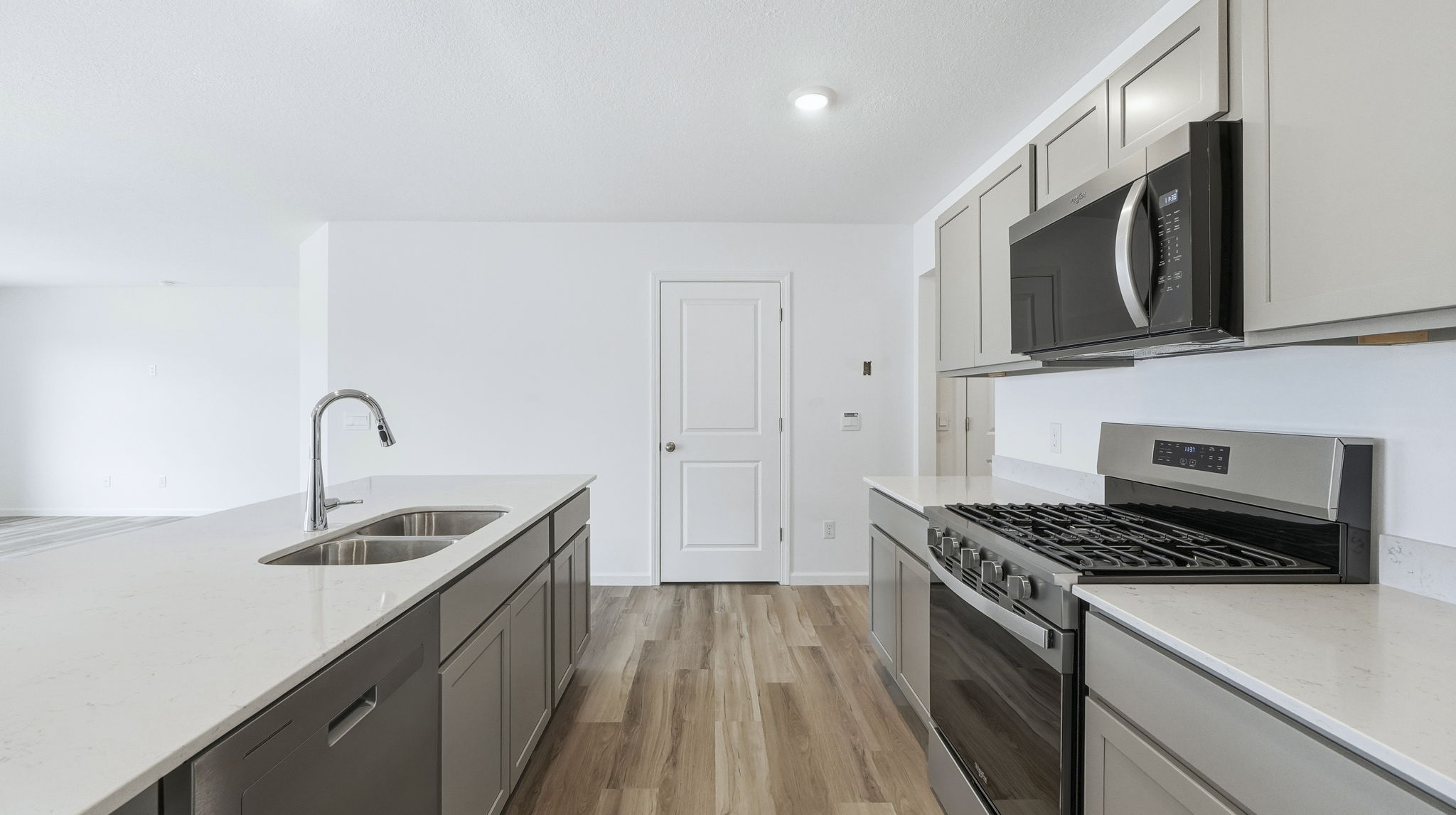kitchen with grey cabinets, stainless steel appliances, large island, and corner pantry