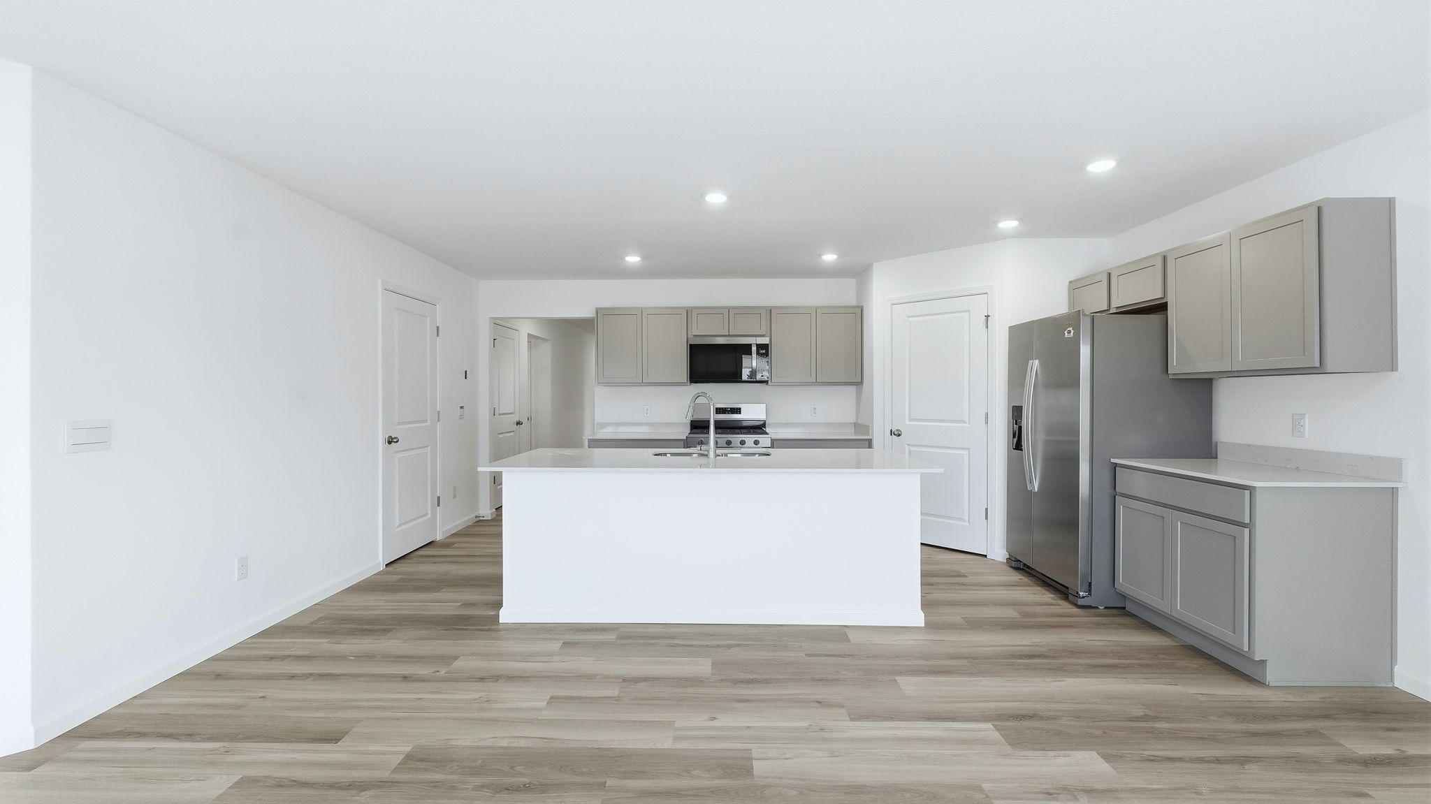 kitchen with grey cabinets, stainless steel appliances, large island, and corner pantry
