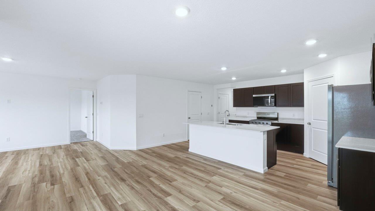 kitchen with sarsaparilla cabinets, quartz countertops, stainless steel appliances, corner pantry, center island, with lvp