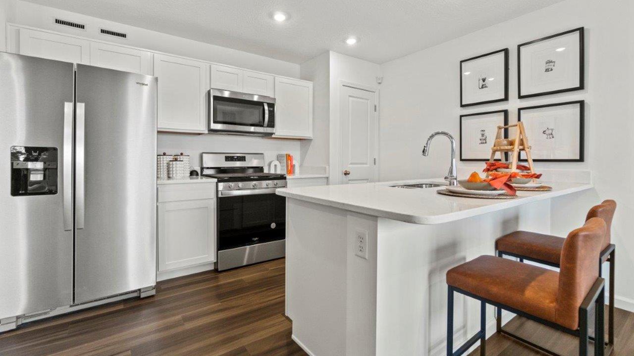 riverwalk aldridge model kitchen with ryder lvp, whirlpool stainless steel appliances, elkins white shaker cabinets, carrara marmi quartz countertops