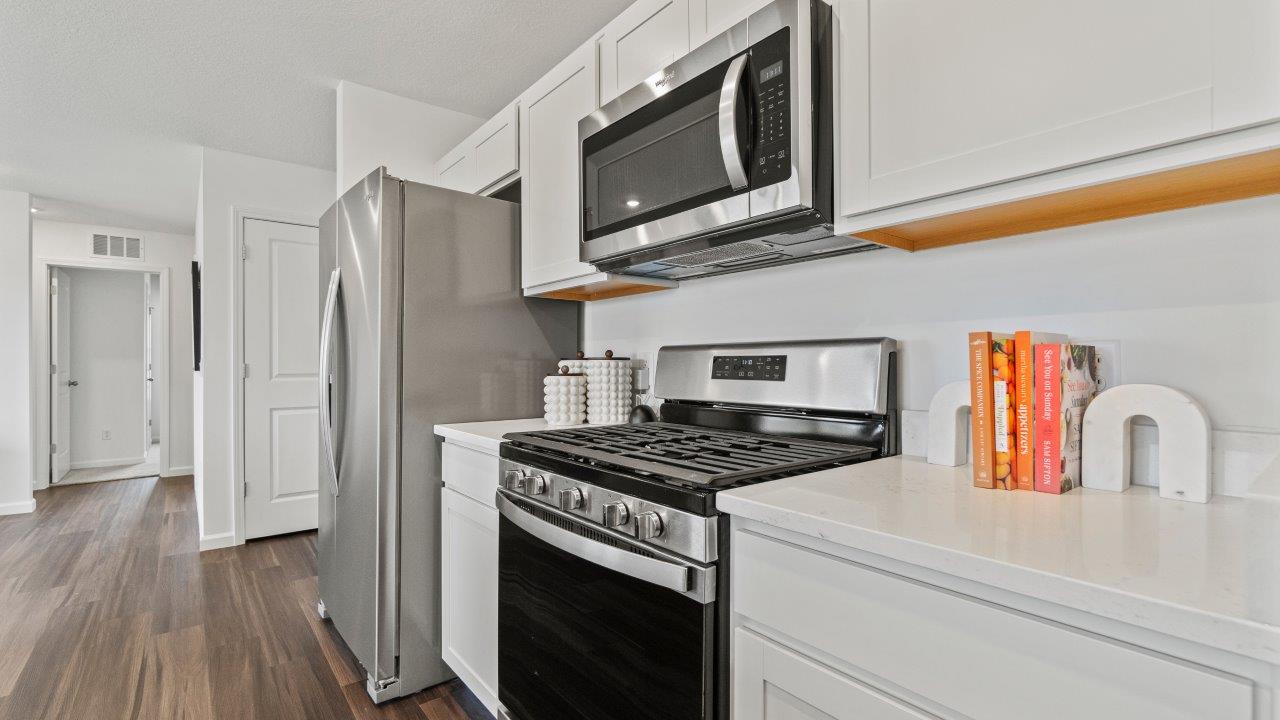 riverwalk aldridge model kitchen with ryder lvp, whirlpool stainless steel appliances, elkins white shaker cabinets, carrara marmi quartz countertops