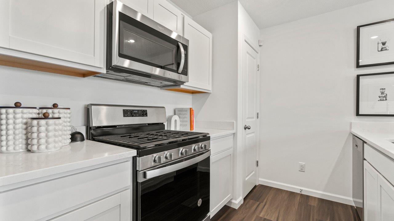 riverwalk aldridge model kitchen with ryder lvp, whirlpool stainless steel appliances, elkins white shaker cabinets, carrara marmi quartz countertops