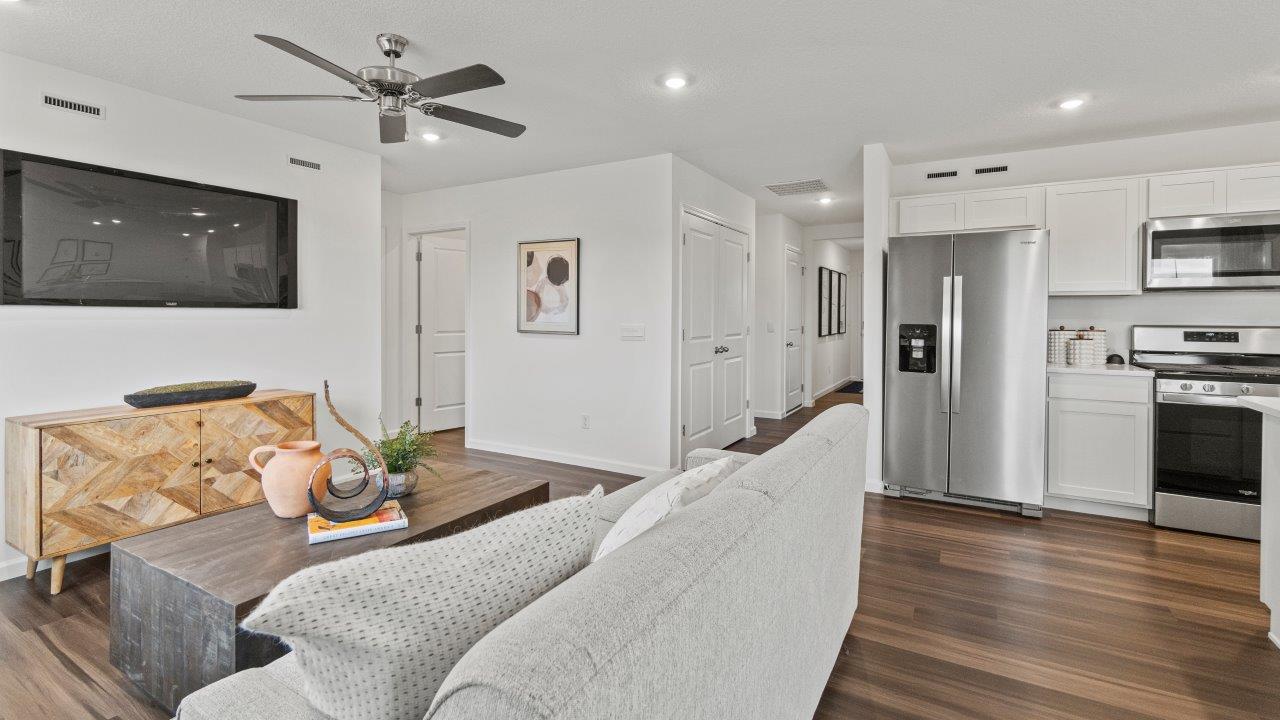 riverwalk aldridge model open layout living room with ryder lvp flooring, ceiling fan, 2 windows, and furnished