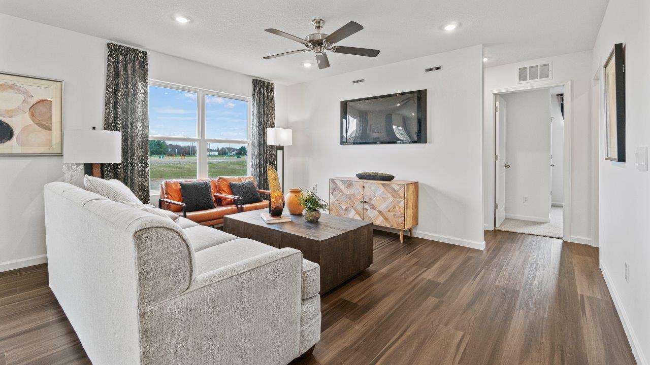 riverwalk aldridge model open layout living room with ryder lvp flooring, ceiling fan, 2 windows, and furnished