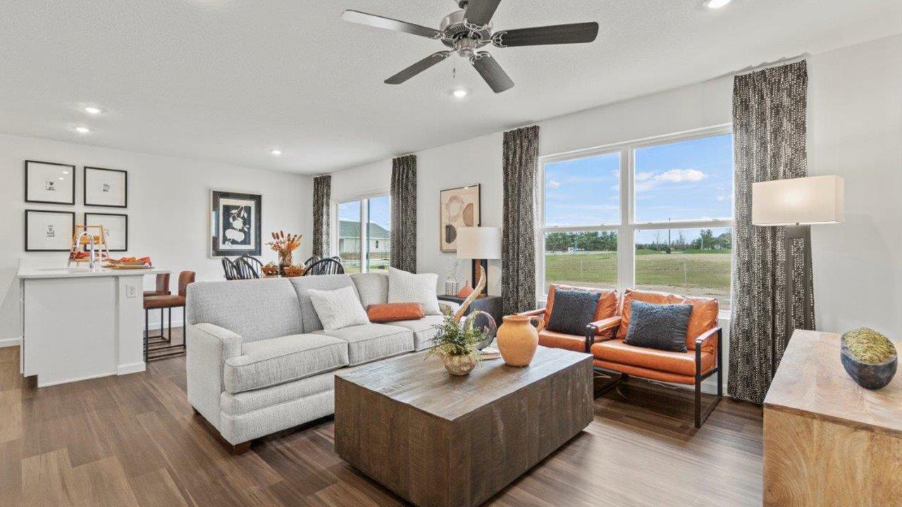 riverwalk aldridge model open layout living room with ryder lvp flooring, ceiling fan, 2 windows, and furnished