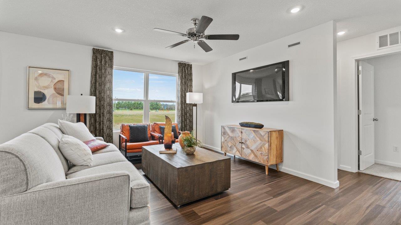 riverwalk aldridge model open layout living room with ryder lvp flooring, ceiling fan, 2 windows, and furnished