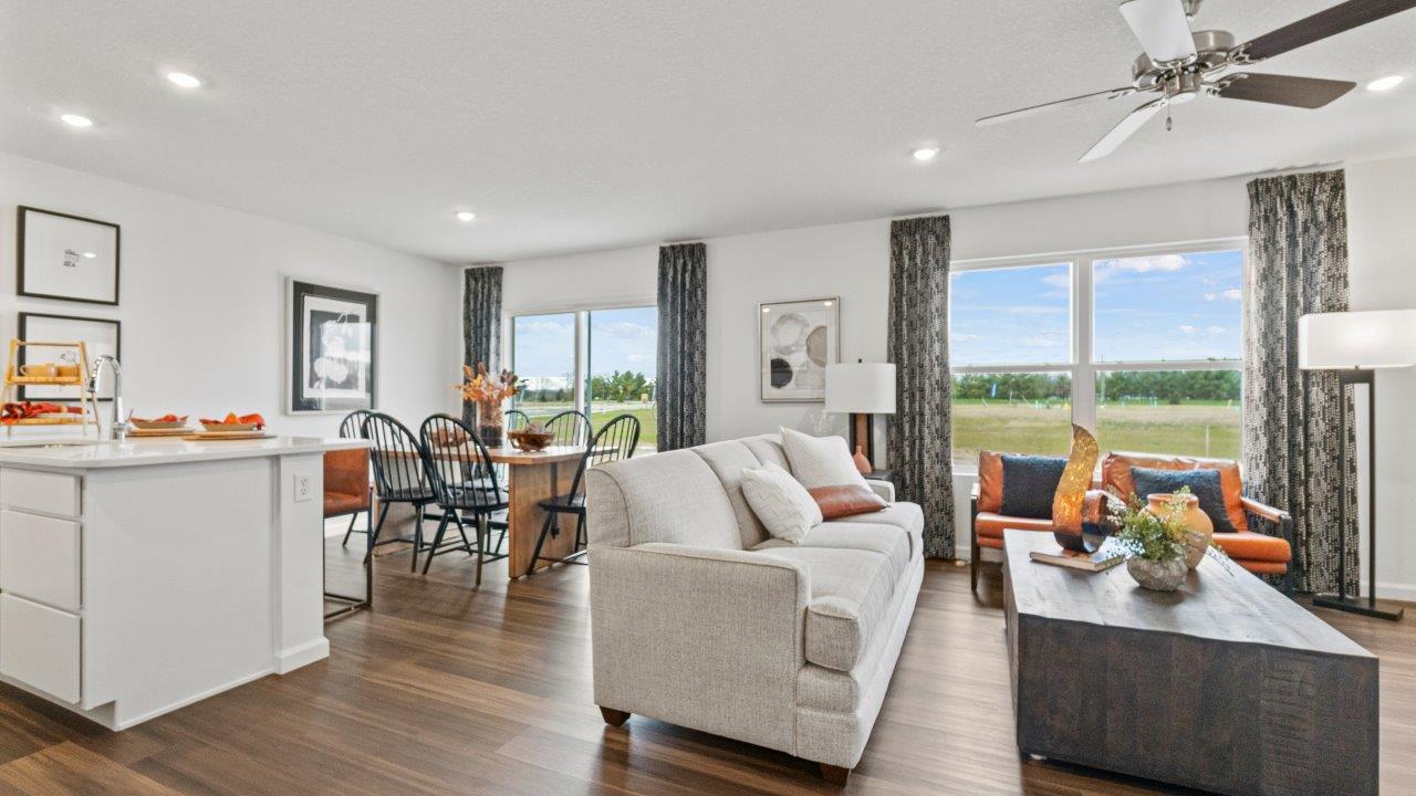 riverwalk aldridge model open layout living room with ryder lvp flooring, ceiling fan, 2 windows, and furnished
