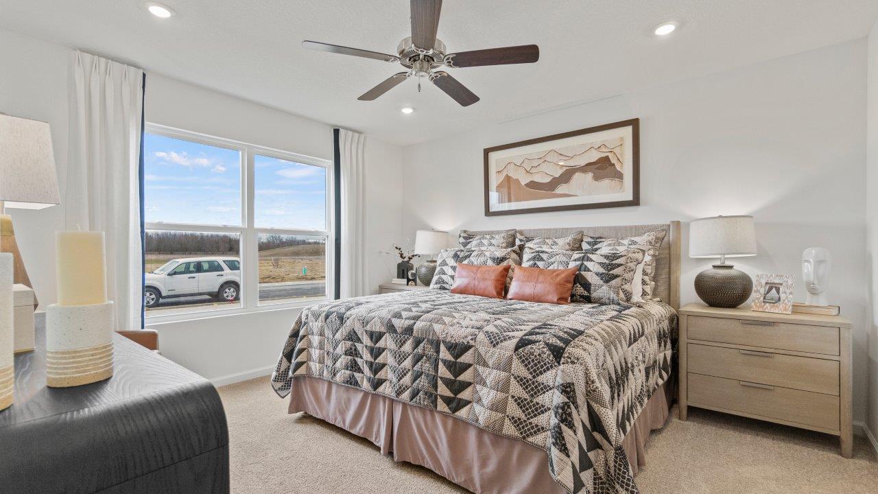 riverwalk aldridge model primary bedroom with ceiling fan, 2 windows, elk beige carpet, and ensuite bathroom and walk in closet
