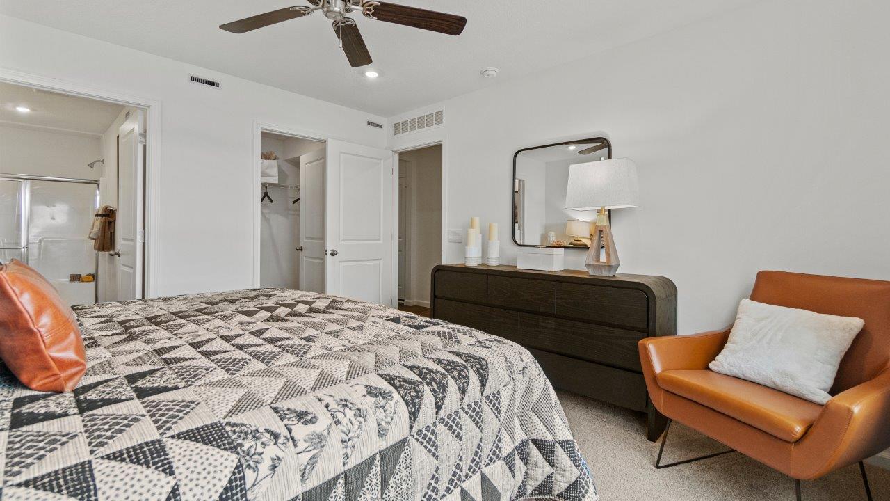 riverwalk aldridge model primary bedroom with ceiling fan, 2 windows, elk beige carpet, and ensuite bathroom and walk in closet