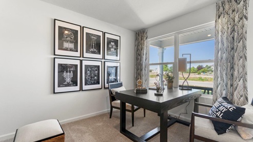 Kennebec Bellamy Model Home First floor flex space decorated as an office with carpet flooring and two windows.