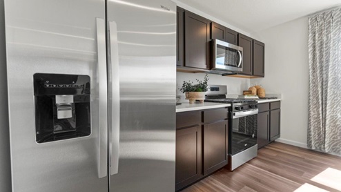 Kennebec Bellamy Model Home Kitchen with stainless steel appliances and LVP flooring.
