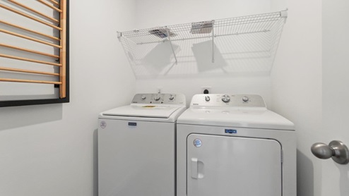 Kennebec Bellamy Model Home Laundry room with wire shelving and washer and dryer with LVP flooring.