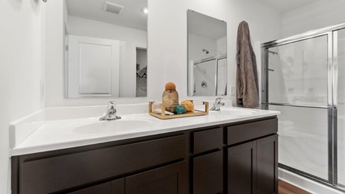 Kennebec Bellamy Model Home Dual vanity bathroom with cultured white marble counters and walk in shower off of main bedroom.