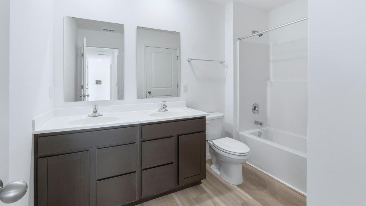 full bathroom with dual sinks and tub shower